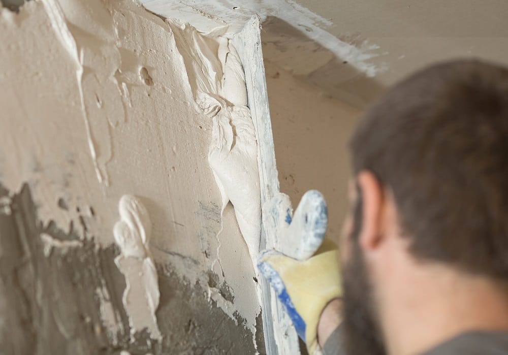 Insulating plaster mortar putty being smeared onto wall in a home renovation