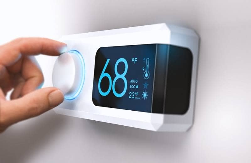 Hand adjusting dial on an energy saving thermostat