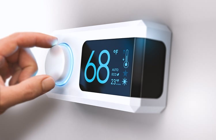 Hand turning a home thermostat knob to set temperature on energy saving mode. Hand turning a home thermostat knob to set temperature on energy saving mode.