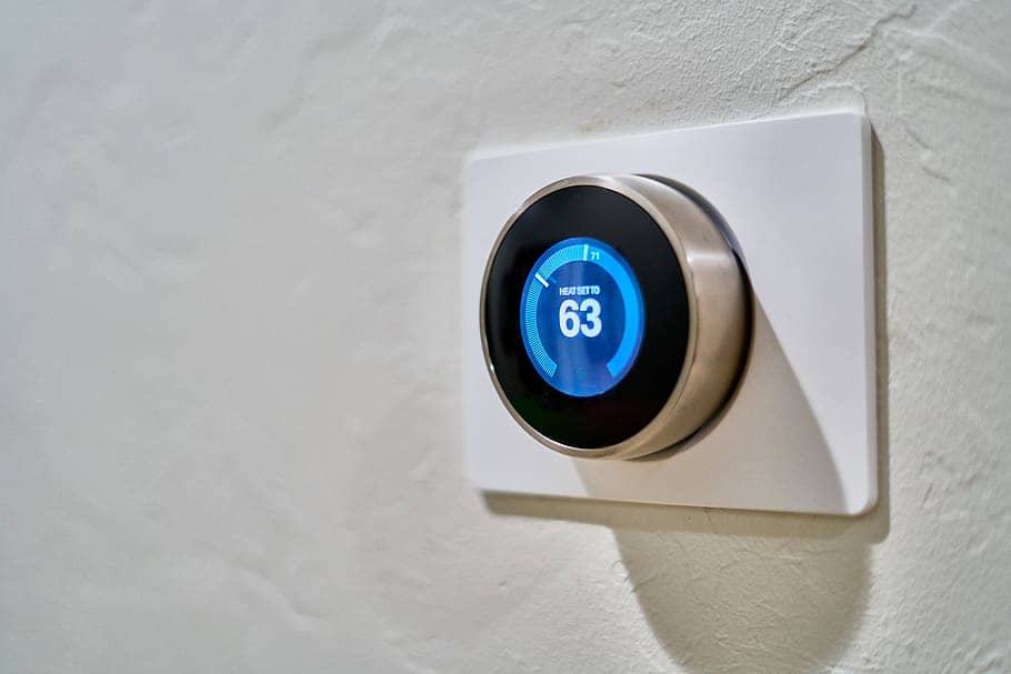 Digital thermostat on white wall Modern round digital thermostat on white wall background