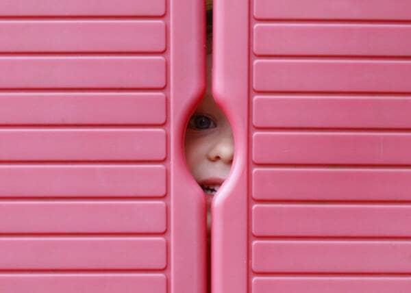 a kid peeping through the dorr of a wendy house