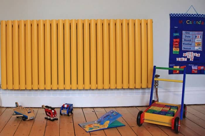 toys on the floor next to a yellow radiator