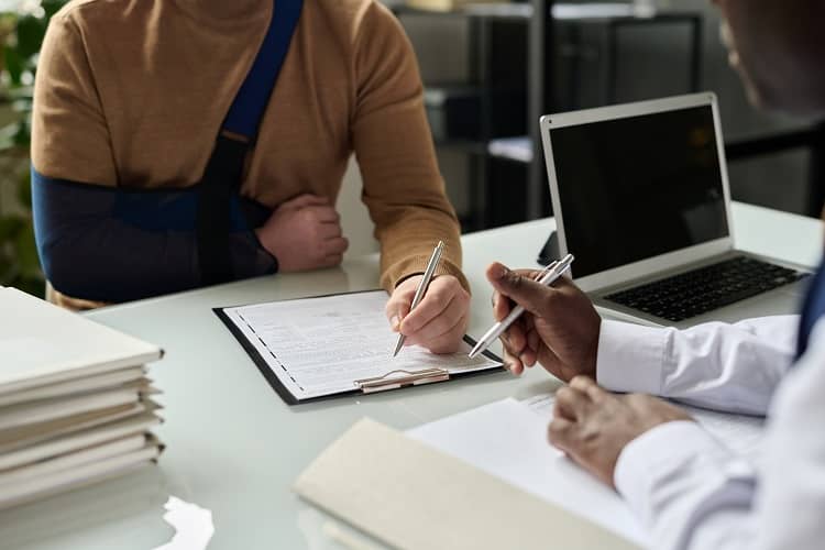 Close up of man filling in medical insurance form following workplace accident