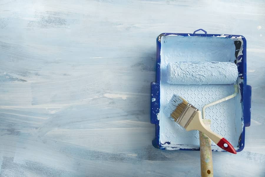 Paint tray, roller and brush on blue background