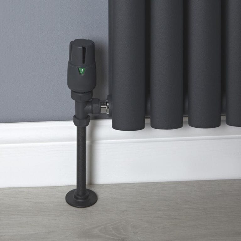 Milano black modern thermostatic angled radiator valve and lockshield attached to black modern radiator on grey wall above white skirting board
