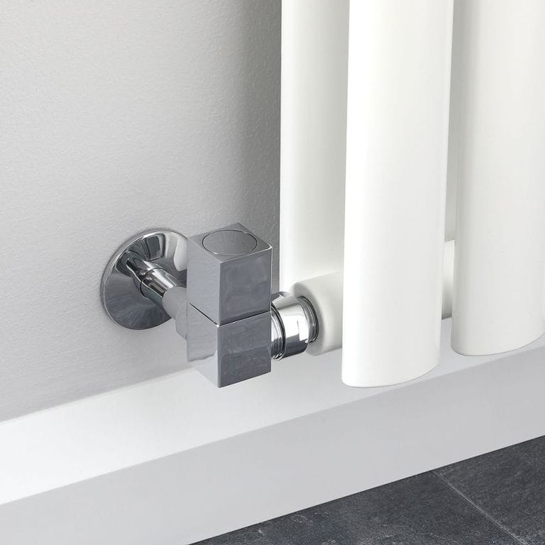 Milano chrome square corner radiator valve attached to white radiator on light wall above white skirting board