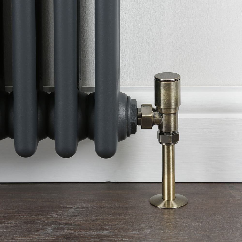 Milano modern dark brushed brass angled radiator valves on wooden floor attached to traditional anthracite radiator