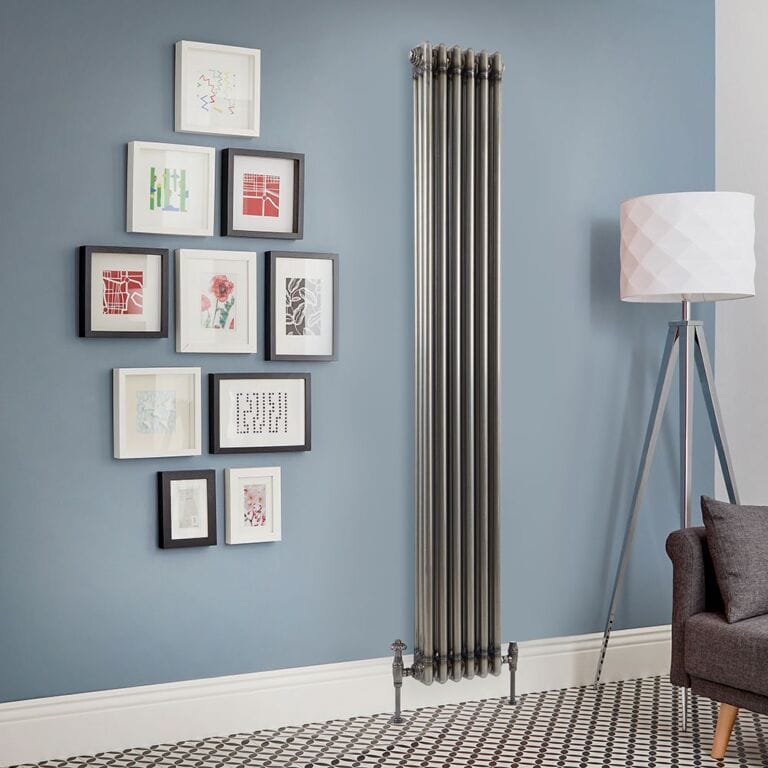 Milano Windsor raw lacquered metal vertical traditional triple column radiator on blue wall nearby tall lamp and multiple pieces of framed artwork