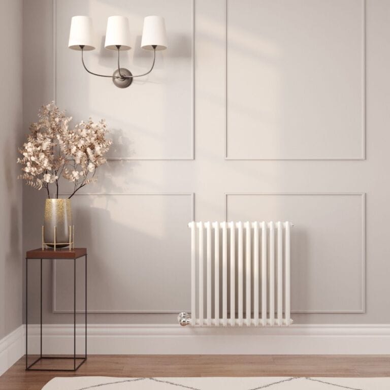 Milano Windsor white traditional horizontal electric double column radiator on light wall nearby gold vase beneath triple light fitting