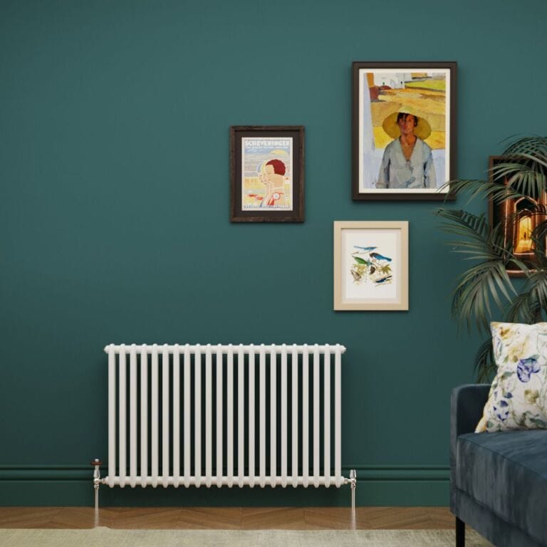 Milano Windsor white traditional horizontal double column radiator on green wall underneath multiple framed art pictures nearby blue chair