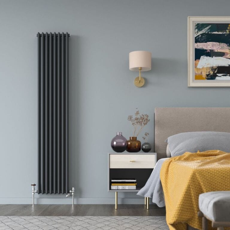 Milano Windsor anthracite traditional vertical dual fuel triple column radiator on light blue wall nearby bedside table and bed beneath artwork and light fitting