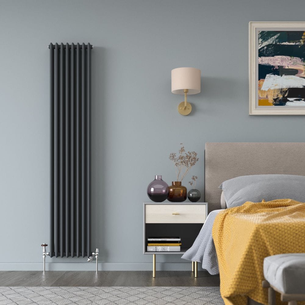 Milano Windsor anthracite traditional vertical dual fuel triple column radiator on light blue wall nearby bedside table and bed beneath artwork and light fitting