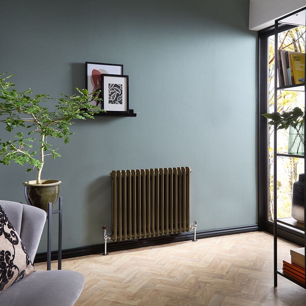 Milano Windsor metallic bronze horizontal traditional double column radiator on blue wall beneath artwork nearby small table with plant
