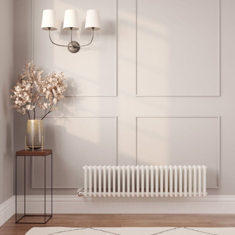 Milano Windsor white traditional horizontal electric triple column radiator on light wall nearby table with gold vase beneath triple light fitting