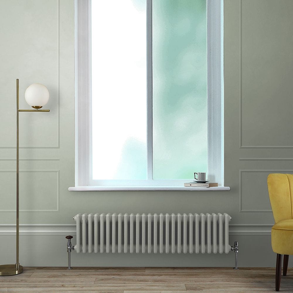 Milano Windsor storm cloud grey horizontal traditional triple column radiator beneath window and next to modern freestanding lamp and yellow chair