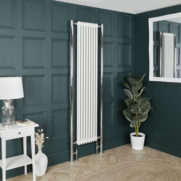 Milano Windsor white vertical traditional double column radiator on green wall nearby houseplant beneath mirror and small white table with lamp