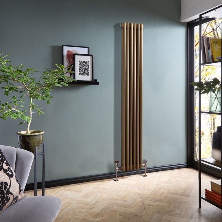 Milano Windsor metallic bronze vertical traditional double column radiator on light blue wall in modern home nearby framed art and houseplant and grey chair