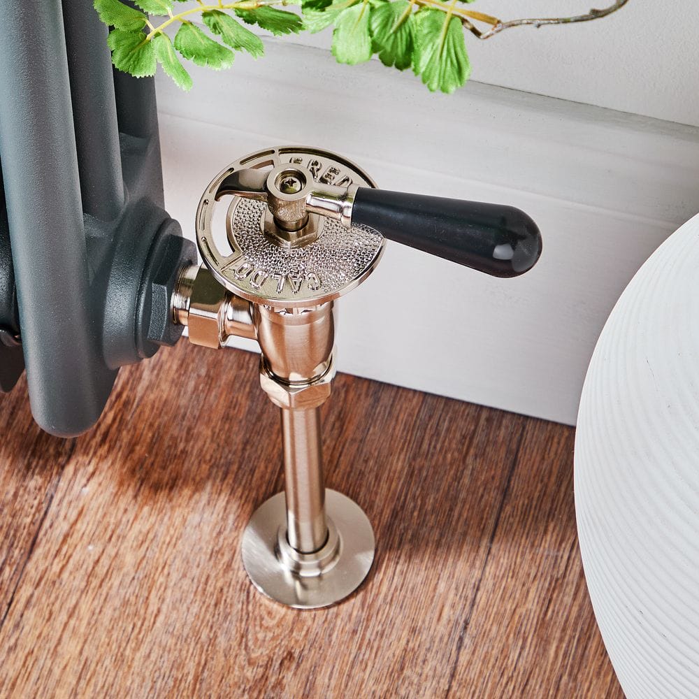 Milano satin traditional thermostatic angled radiator valve and pipe set on wooden flooring attached to traditional radiator