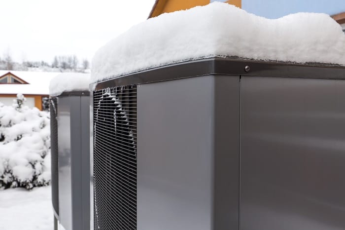 Pair of residential modern heat pumps covered in snow Pair of residential modern heat pumps covered in snow