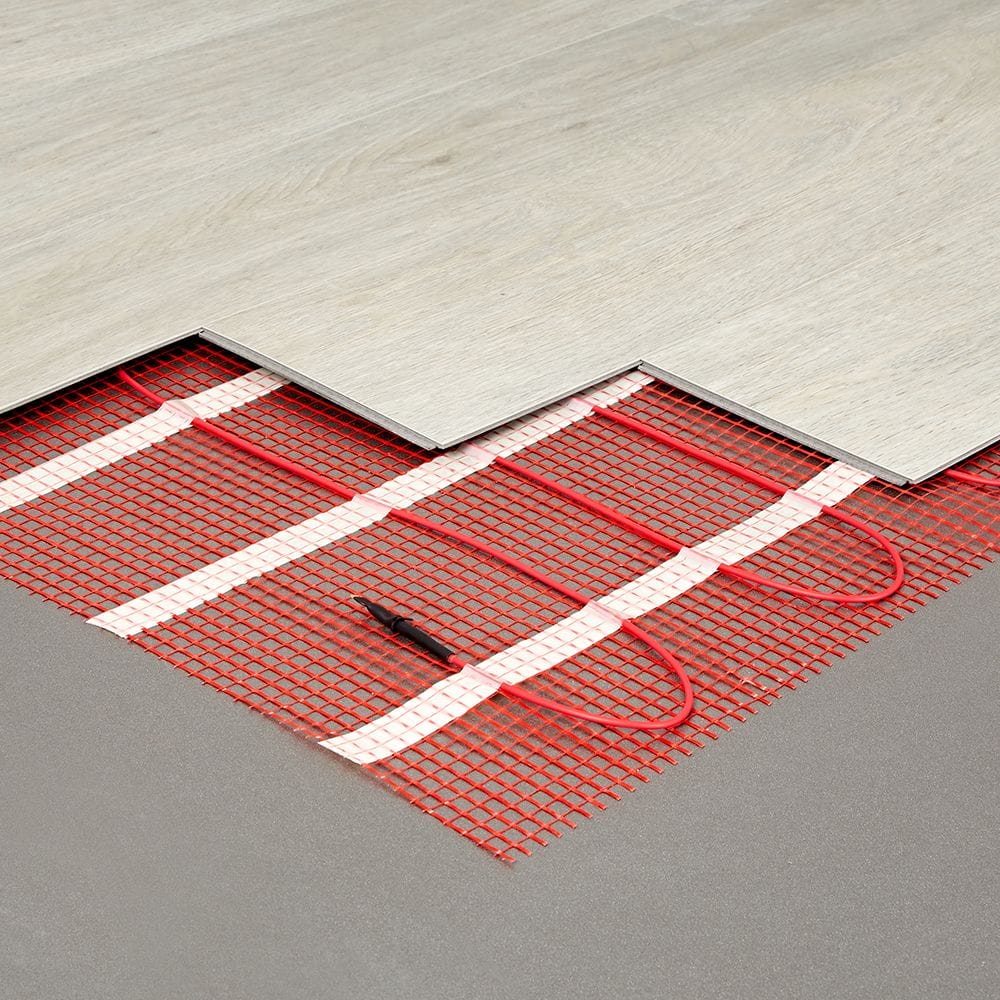 Electric underfloor heating mat with red wiring beneath thin wooden flooring