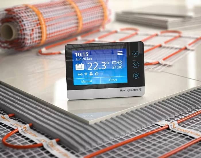 Smart digital thermostat on tiling nearby electric underfloor heating mats
