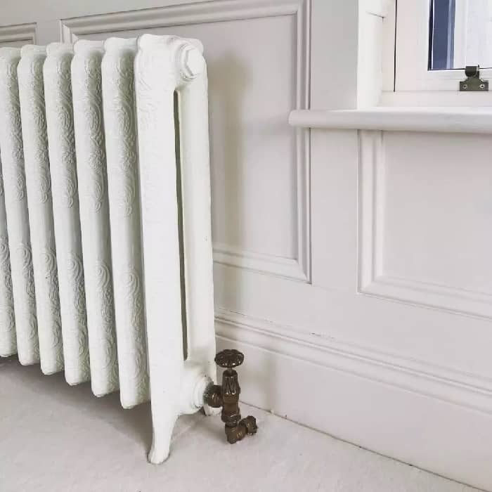 A white cast-iron radiator with ornate detailing.