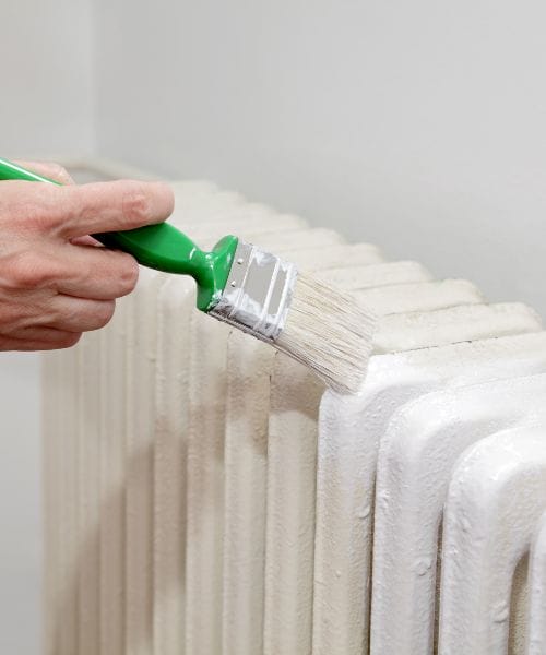 Hand painting a traditional white radiator with white paint