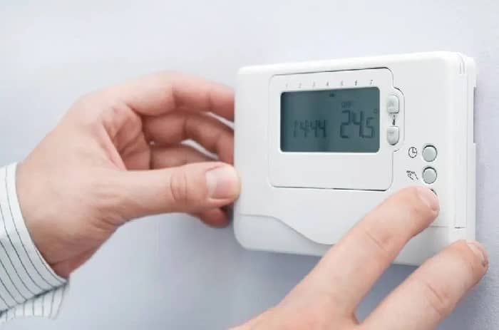 Close up shot of hands switching on a white thermostat