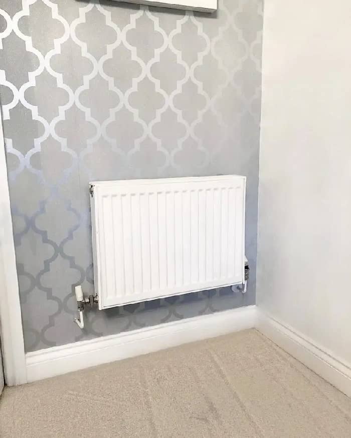 A white convector radiator on a grey wall.