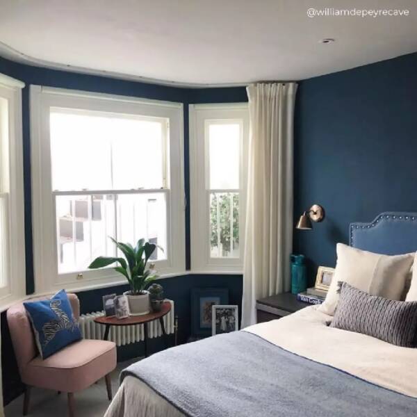 4 white low level radiator under a window in a blue bedroom