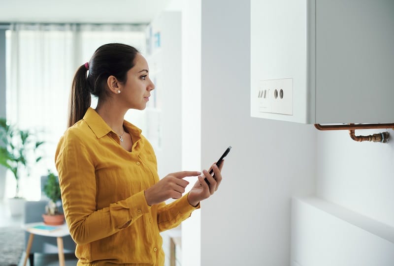 A woman checking if her boiler is working properly to check her cold radiators A woman checking if her boiler is working properly to check her cold radiators