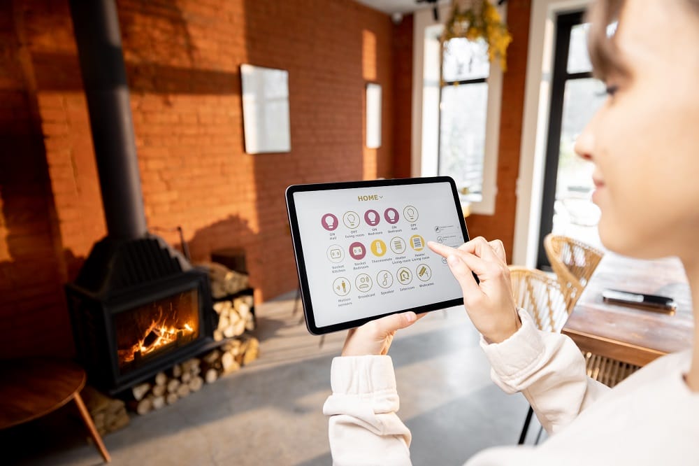 Woman controlling home heating with smart device Woman using smart device to control home heating in front of fireplace and brick wall
