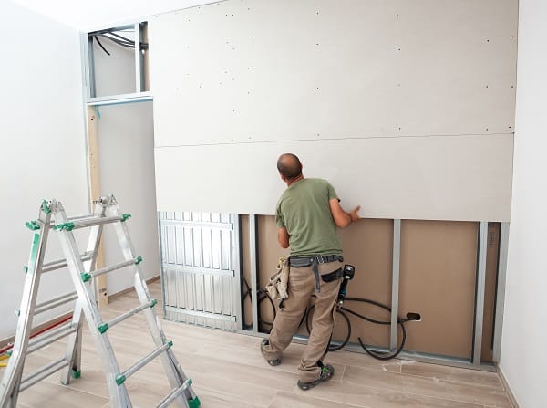 Worker building plasterboard wall. Working with cutting tools, fixing and measuring for drywall. Worker building plasterboard wall. Working with cutting tools, fixing and measuring for drywall.