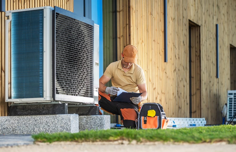 Worker sat outside modern home installing modern heat pump