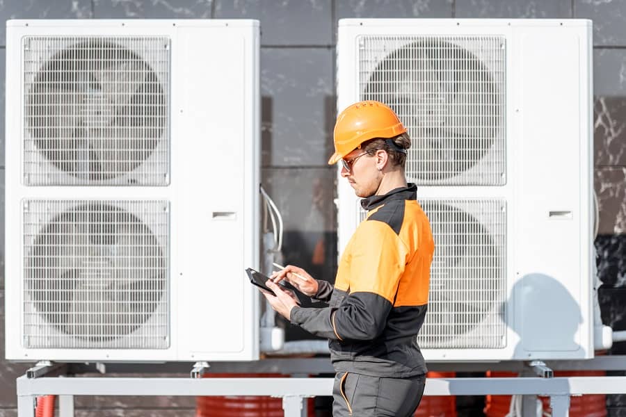 Workman servicing air source heat pumps with an interactive tablet