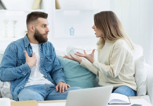 couple sat on a sofa arguing